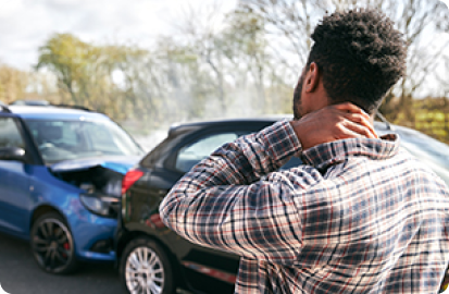 image of man holding neck and looking at car crash