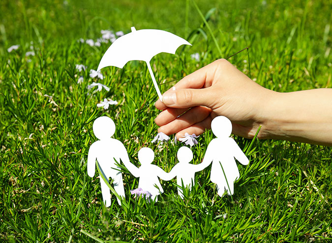 Paper cut out of umbrella over family figurines